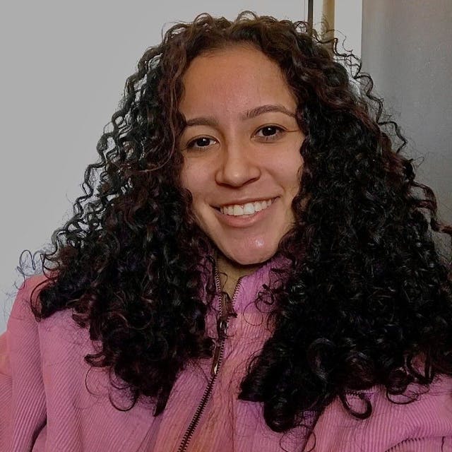 Gabriela, a woman with curly hair, wearing a pink jacket